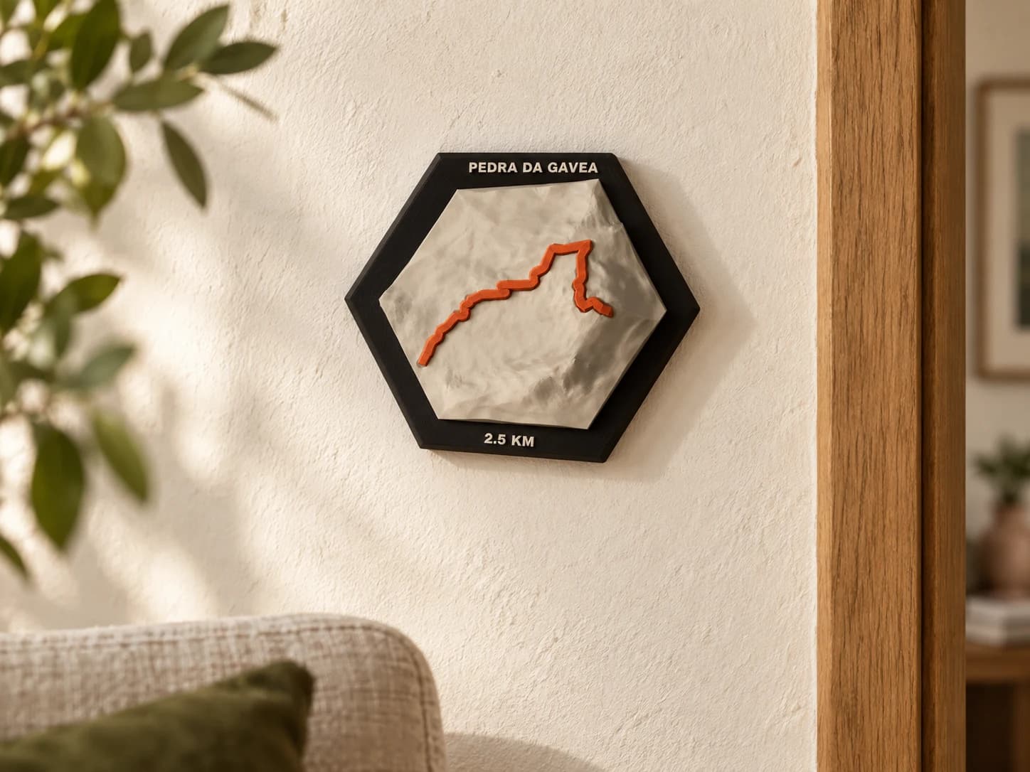 Ambientação ilustrativa da peça hexagonal Pedra da Gávea em parede clara, perto de uma poltrona e de uma porta de madeira.